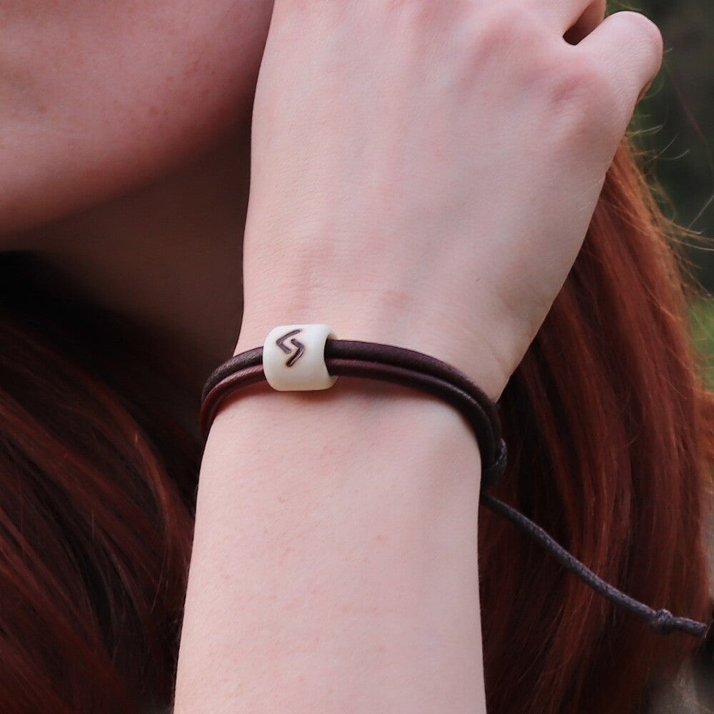 Viking Rune Protection Bracelet on leather and bone, featuring a carved rune bead on a brown cord.