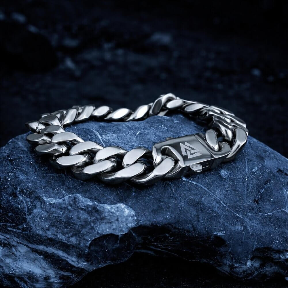 Viking stainless steel chain bracelet with a Valknut rune clasp, resting on a dark stone.