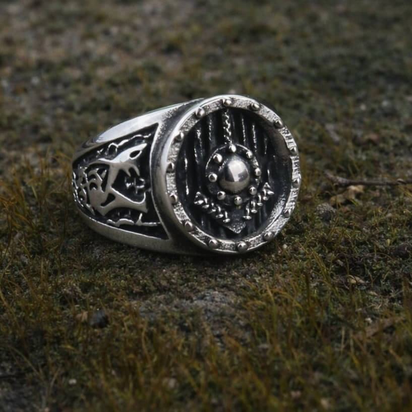 Viking Shield Ring with Tyr Rune in silver, featuring engraved shield face and intricate Nordic details on mossy ground