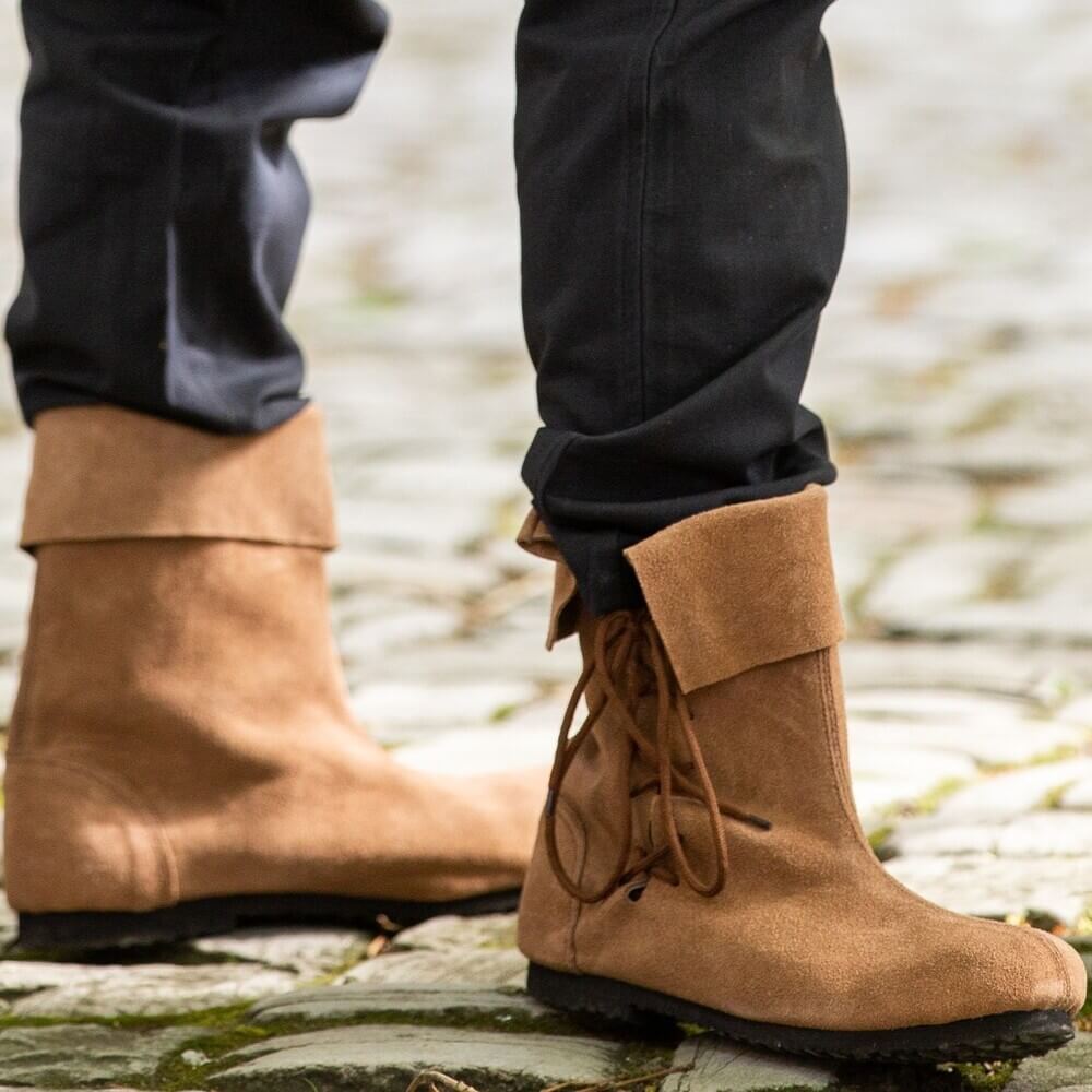 Person standing on cobblestones wearing Viking Sigurd brown suede boots with soft fold-over tops and side laces.