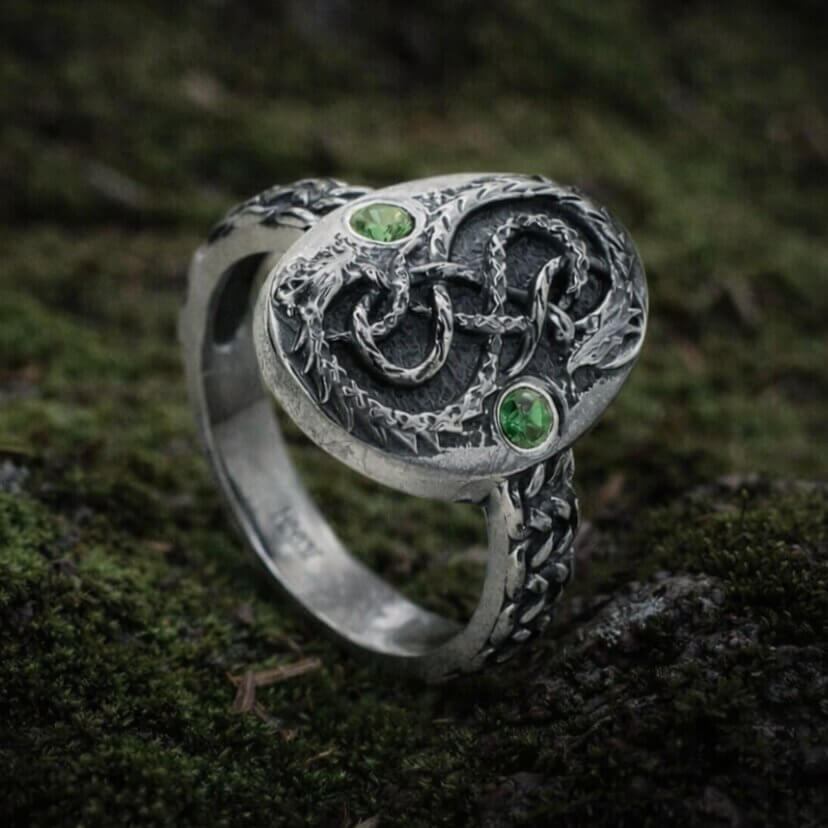 Viking silver serpent ring with intricate knotwork, two green stones, and textured band.