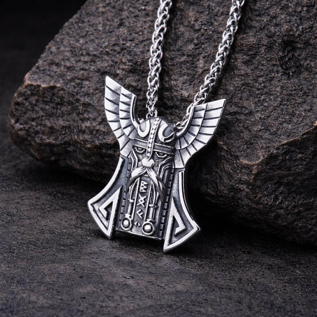 Antiqued Viking Stainless Steel Thor's Hammer Wing Necklace featuring helmeted Odin portrait, spread wings, rune inscriptions, and Valknut symbols on braided wheat chain displayed on stone