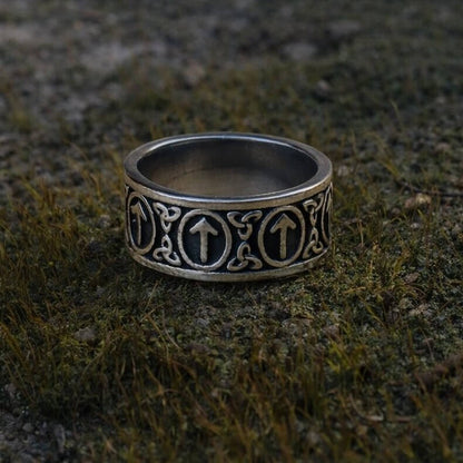 Viking Tyr Rune Band Ring in silver with repeating upward Tyr symbols and intricate Nordic knotwork on mossy ground