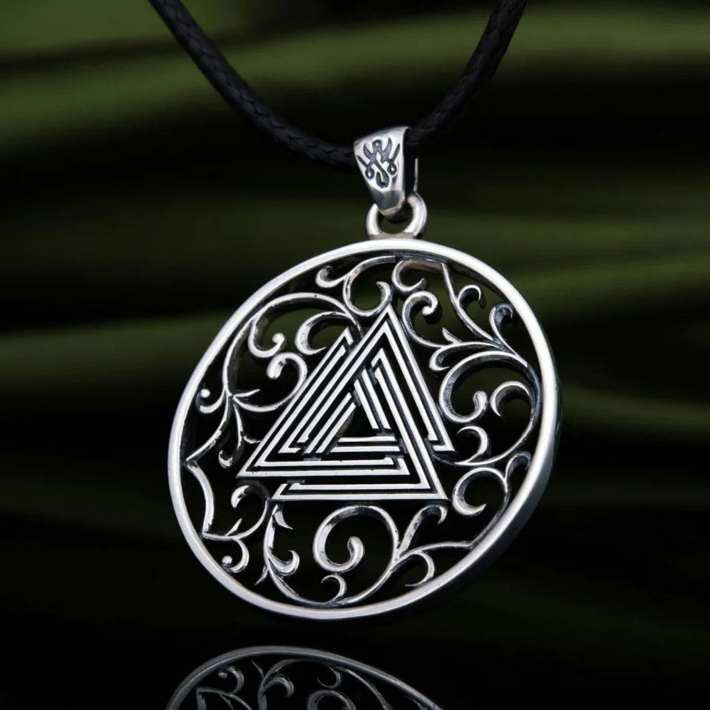 Silver round medallion with interlocking triangle symbol, ornate scrollwork filigree design, and leather necklace