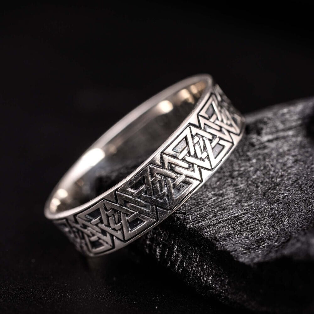 Viking Valknut pattern silver band ring with intricate knotwork on a dark background.