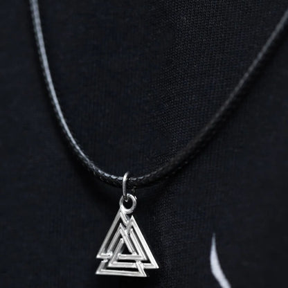 Viking silver Valknut pendant on a black braided cord, against a dark background.