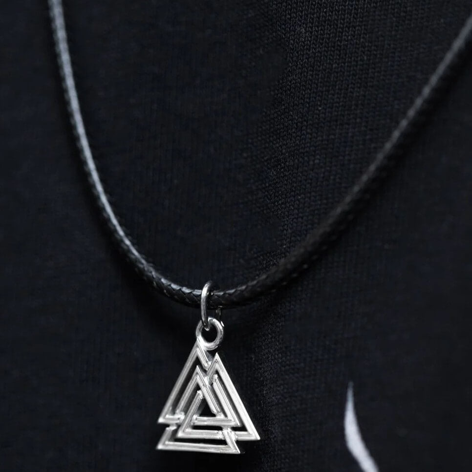 Silver interlocking triangle charm necklace worn on black leather braided cord