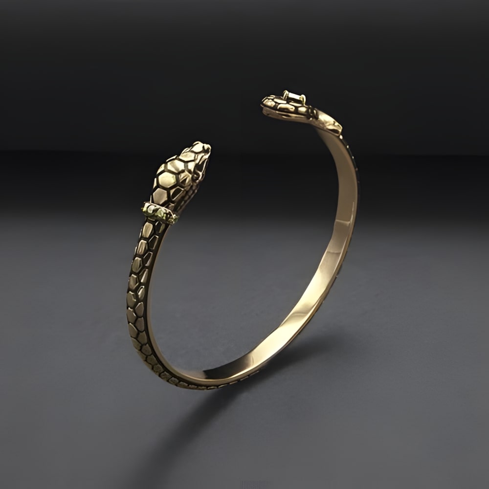 Gold Viking Viper Serpent Bracelet with open ends shaped like snake heads, one set with a small gemstone.