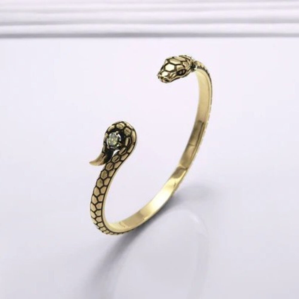 Gold Viking Viper Serpent Bracelet with open ends shaped like snake heads, one set with a small gemstone.